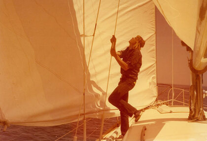 A photograph shows Gerald Hartwig hoisting a sailboat's sail.