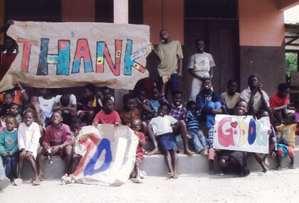 Children and staff of the New Life Orphanage pose for a photo and hold thank you signs.